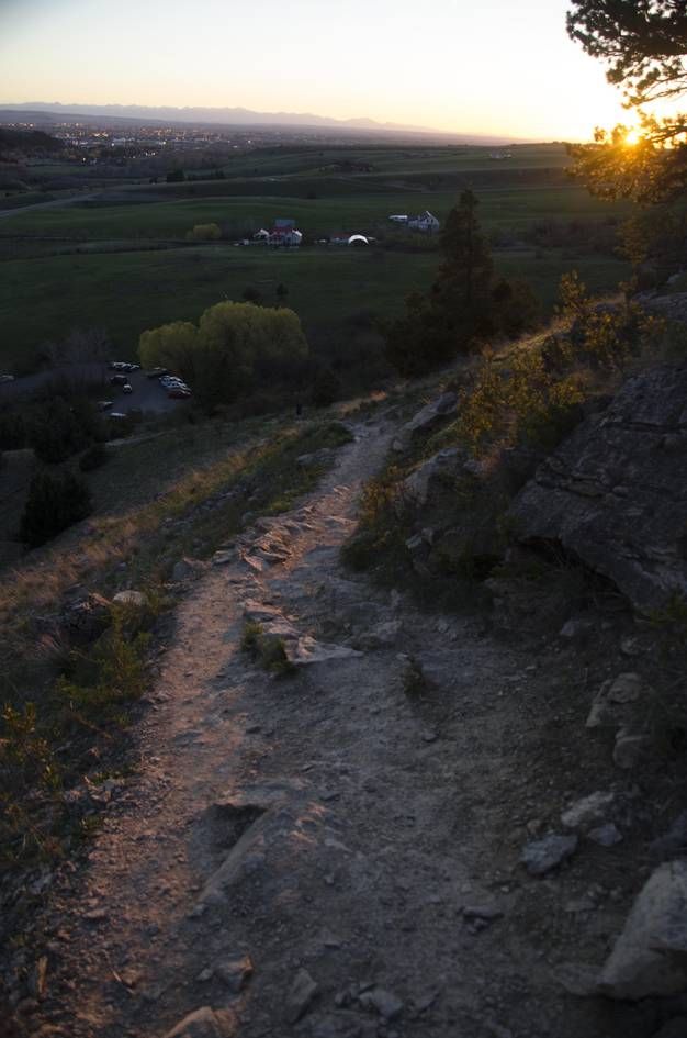 Steep rocky trail descending at sunset toward parking lot