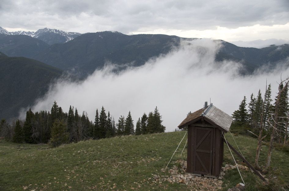 Historic wooden outhouse at fire lookout with clouds filling valley below