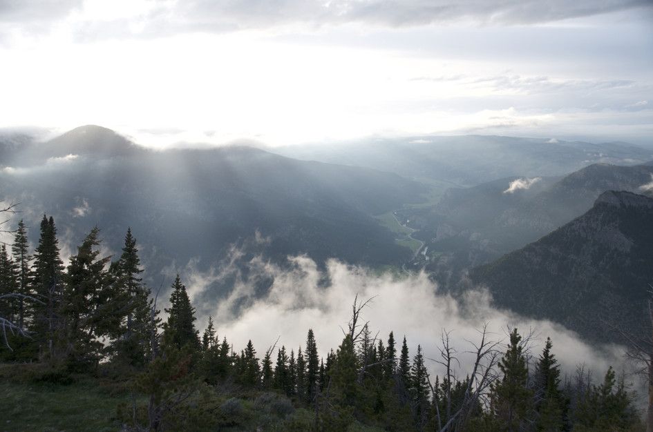 Sun rays breaking through clouds above misty Gallatin Canyon valley