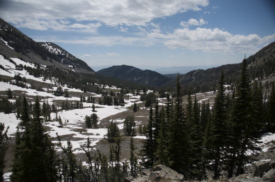 Expansive view from ridge of snow-patched valley and surrounding peaks