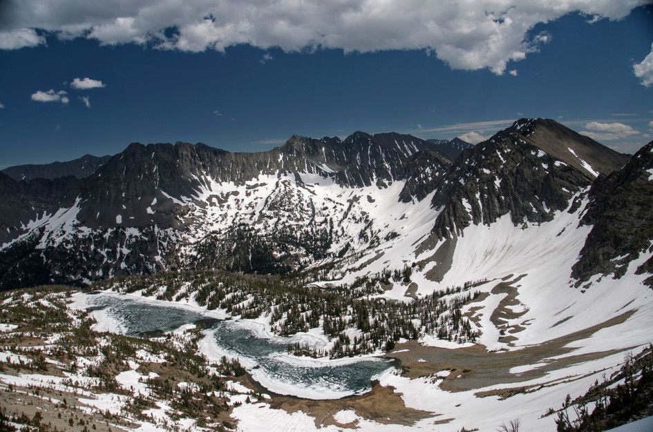 Frozen Campfire Lake in alpine basin surrounded by snow-covered peaks in the Crazy Mountains
