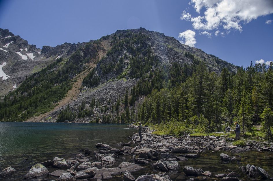 Louise Lake rocky shoreline with hiker and steep forested mountainside