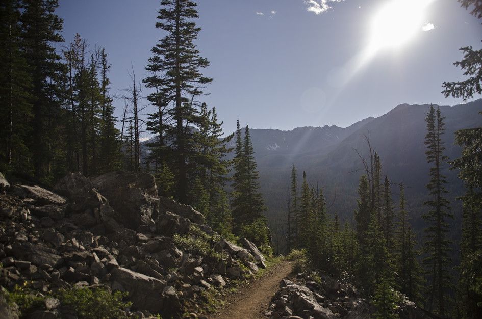 Trail through rocky terrain with sun rays and mountain silhouettes