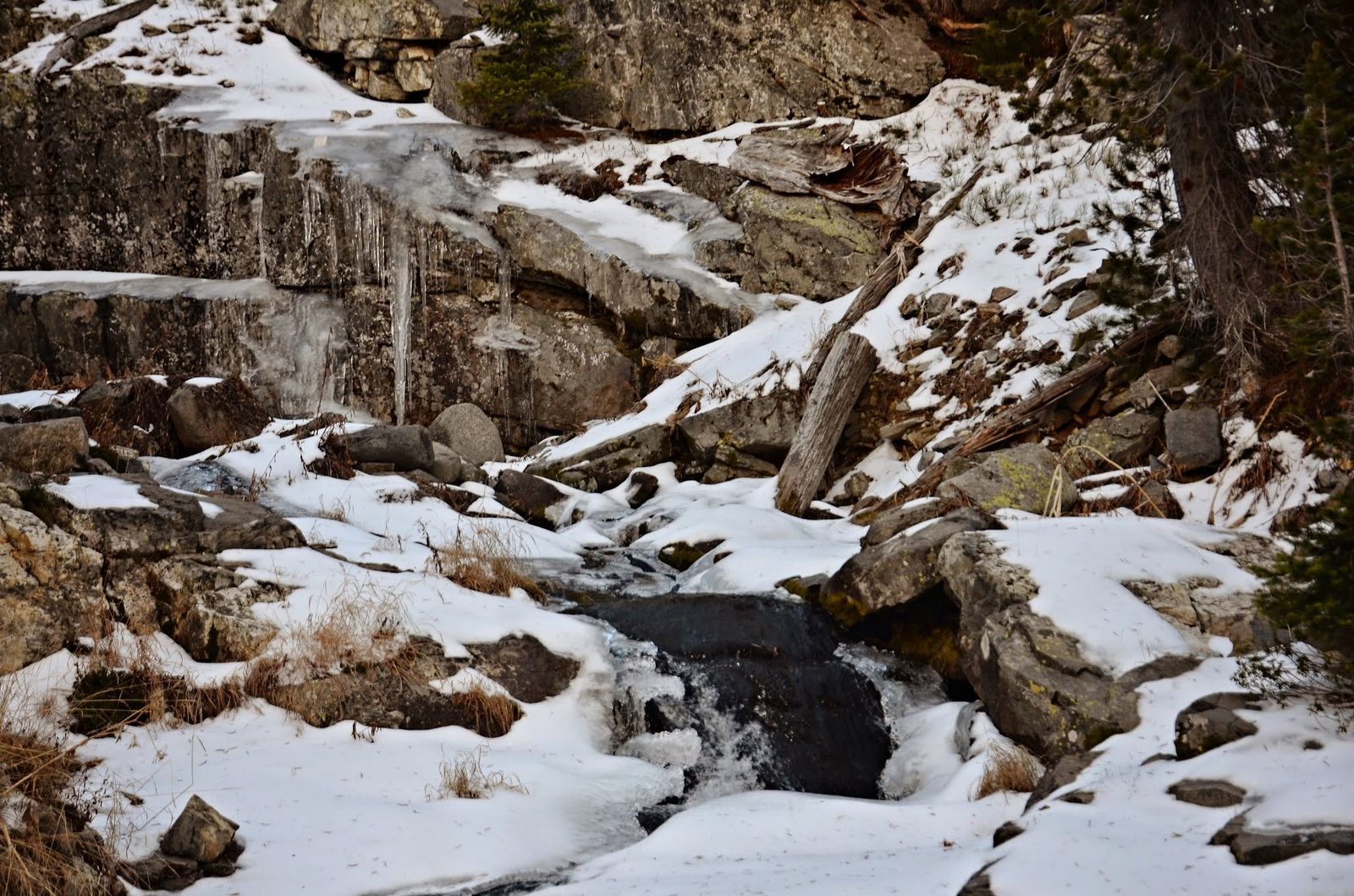 Partially frozen waterfall cascading over icy rocks with snow