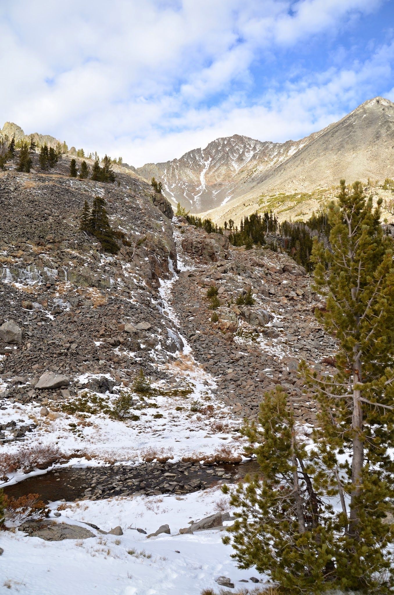 Frozen Cottonwood Creek waterfall with rocky slopes and distant peaks
