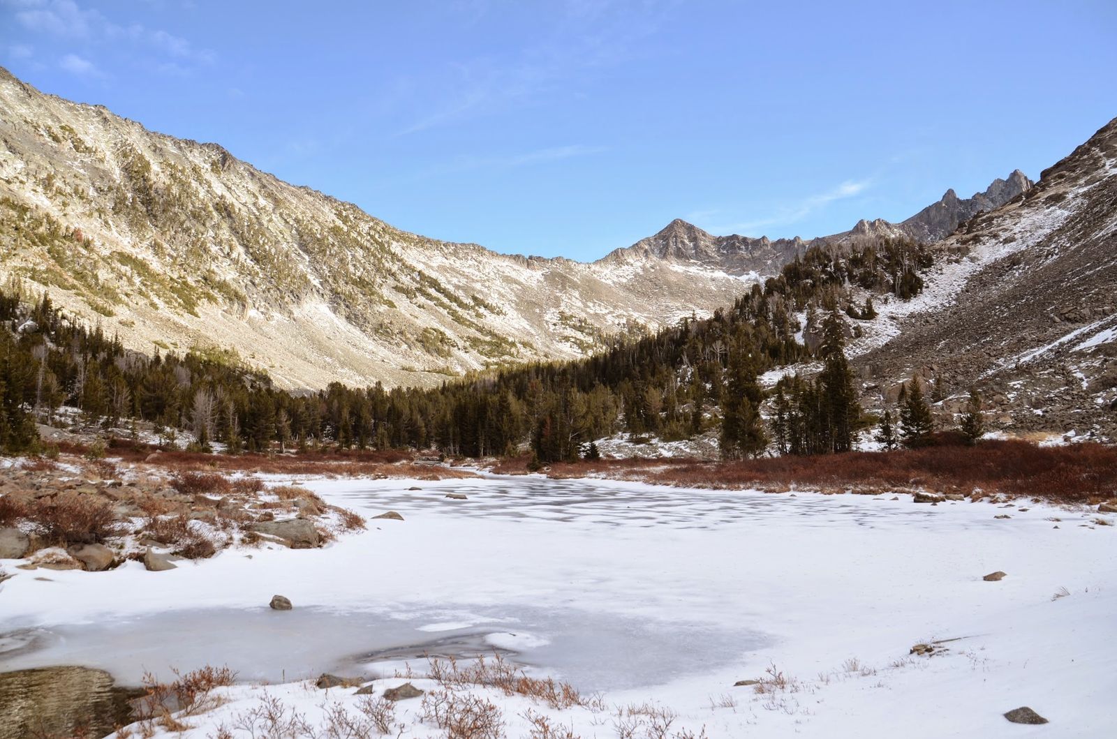 Frozen Cottonwood Lake in alpine cirque surrounded by Crazy Mountain granite peaks