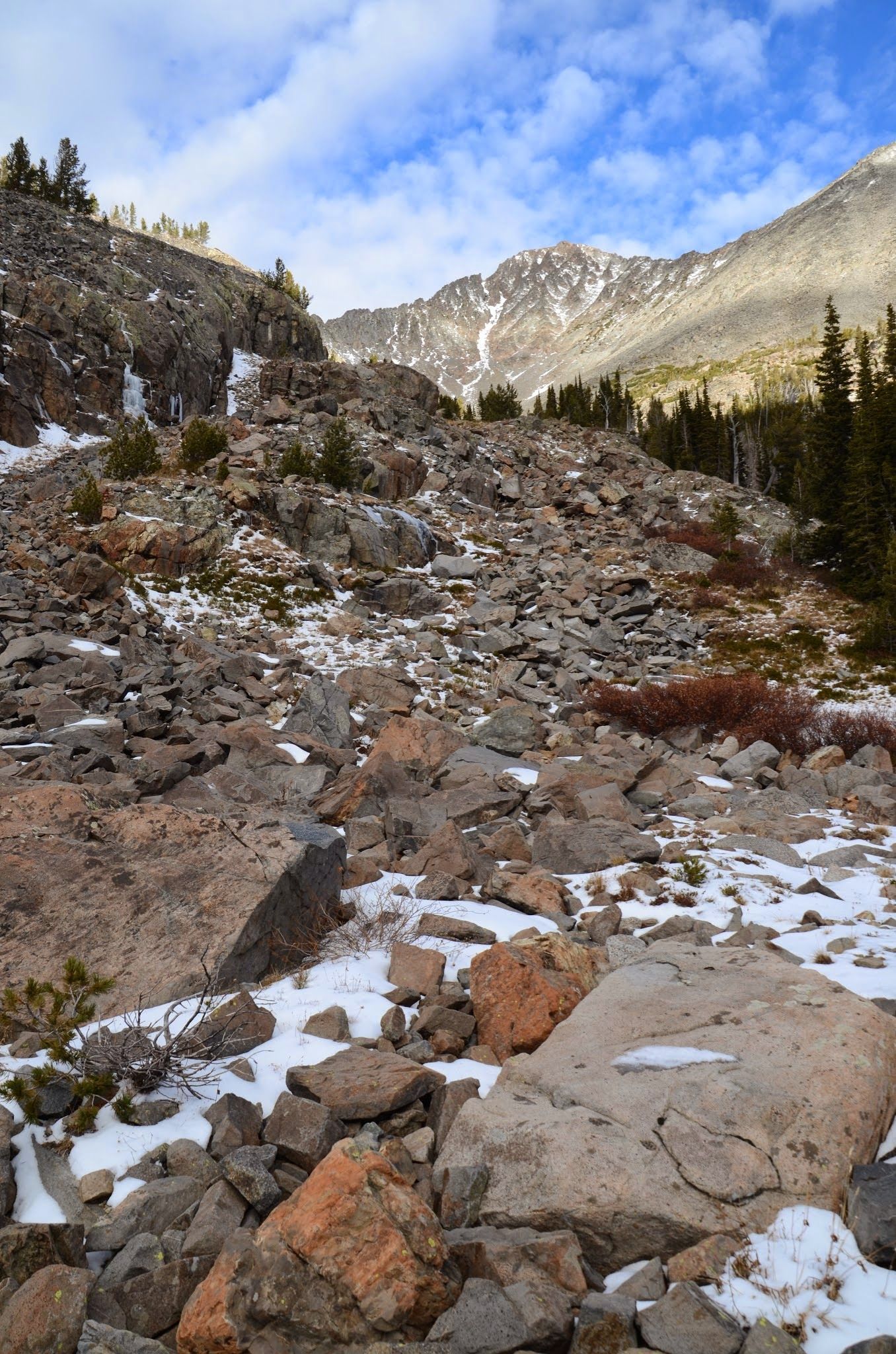 Massive boulder field with snow patches leading to granite cirque walls