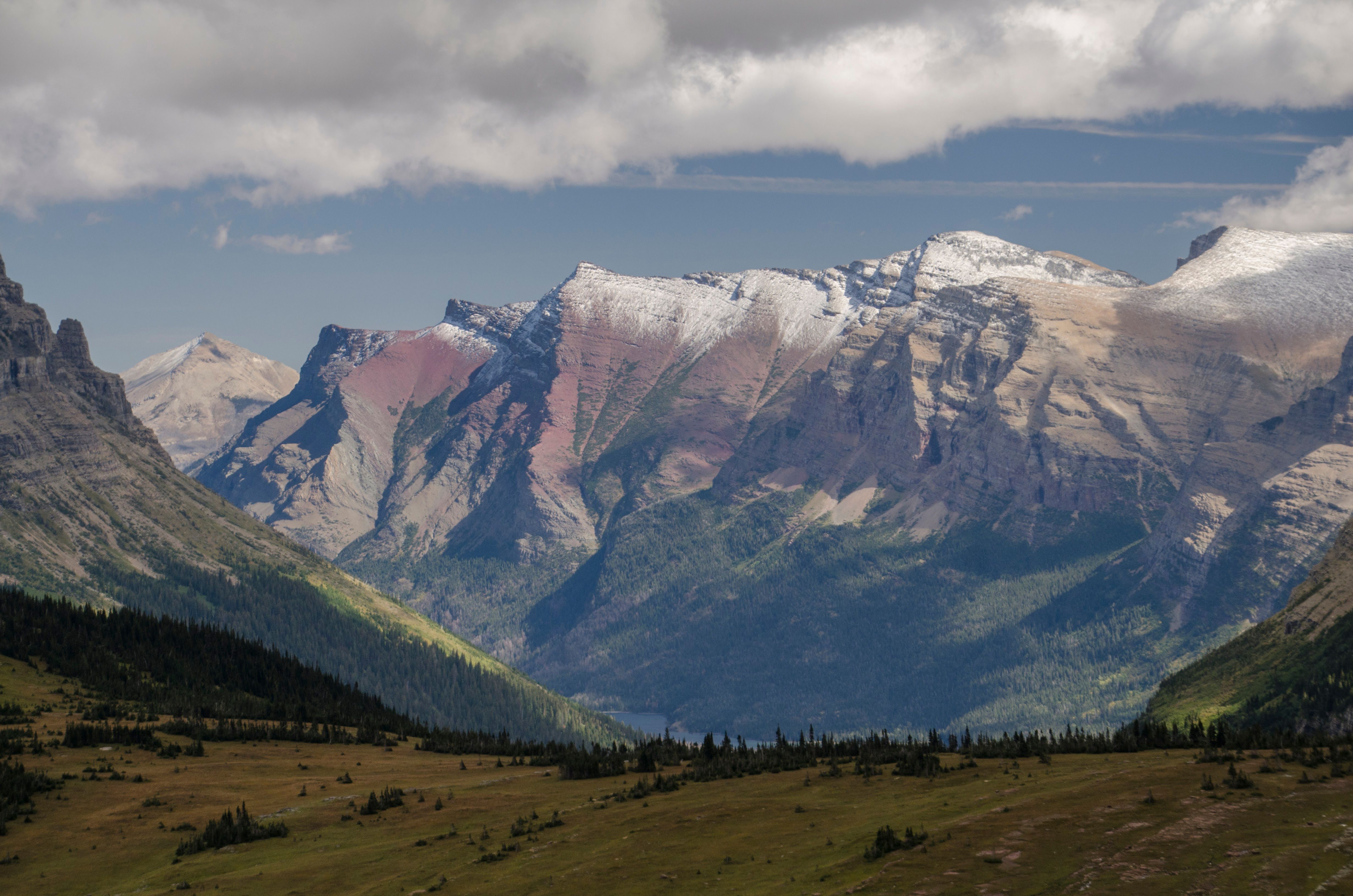 Snow-covered mountain range with forested valley and distant lake below