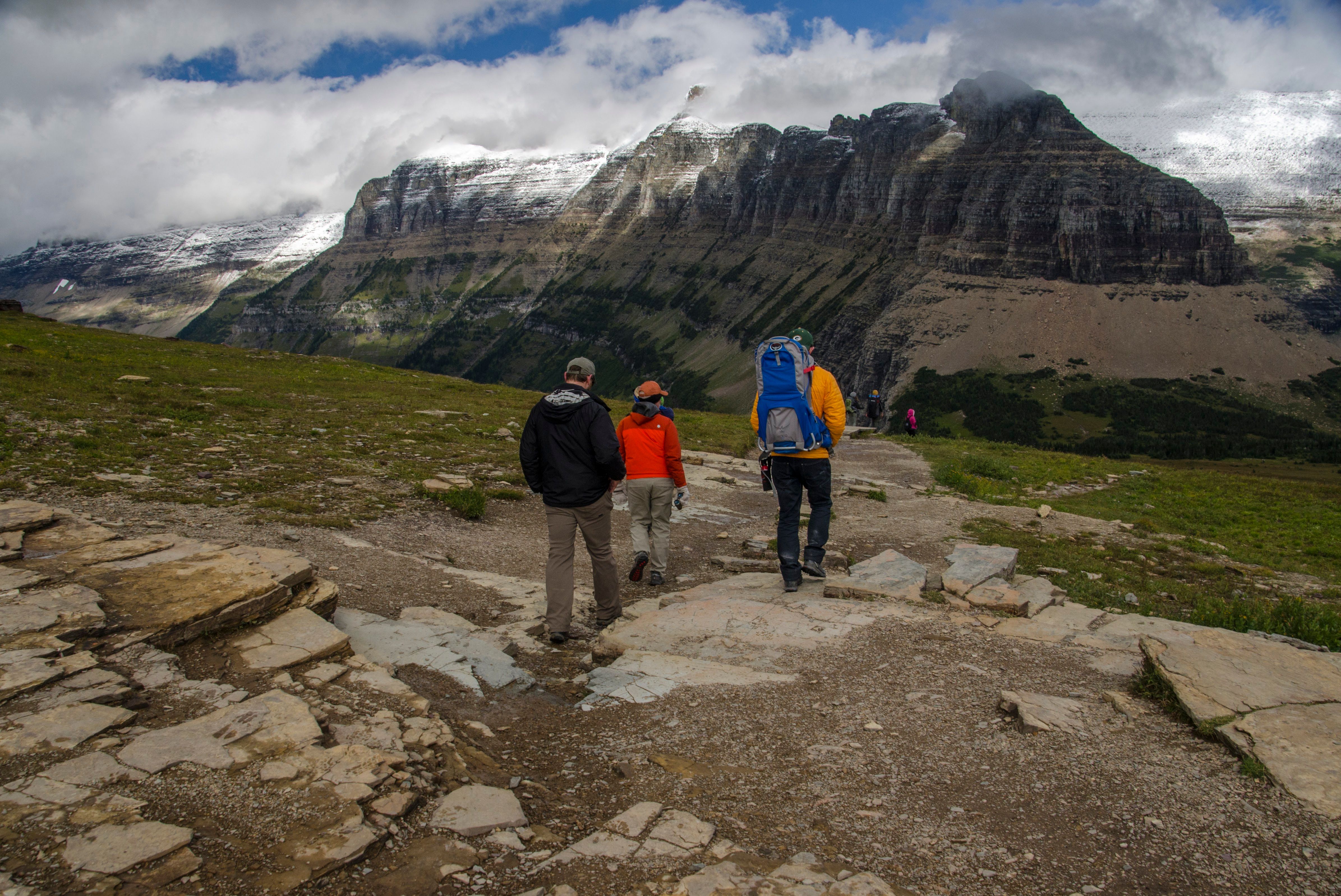 Three hikers walking toward massive snow-capped Bearhat Mountain