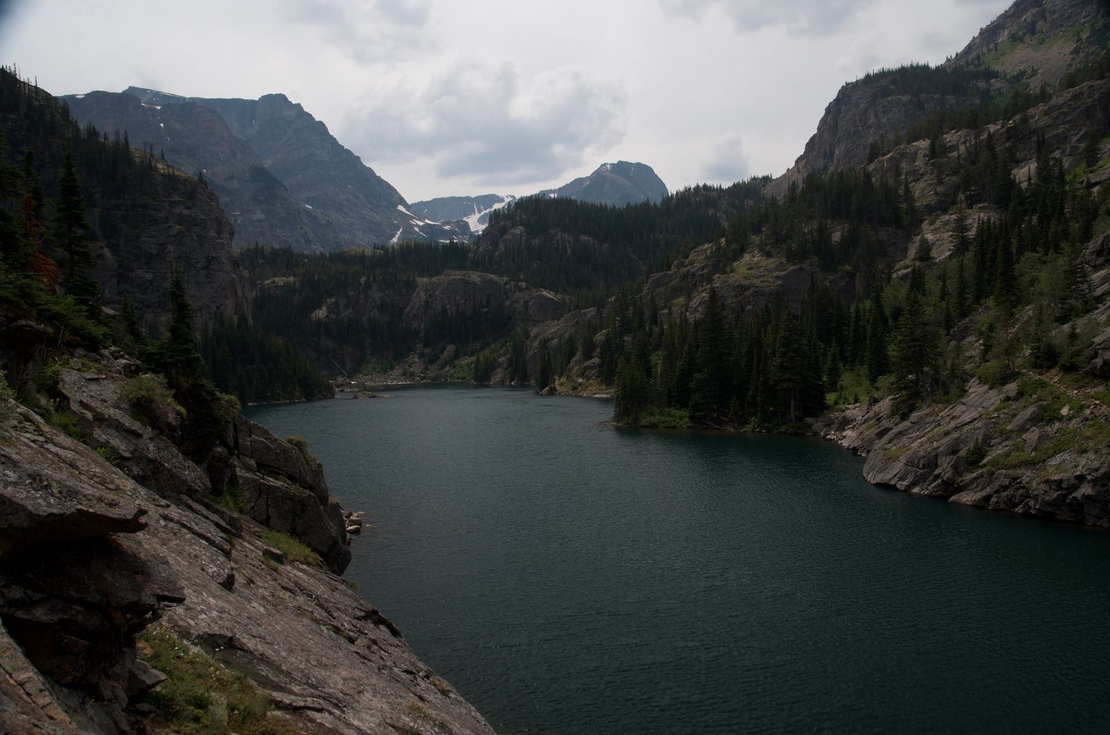 Deep alpine lake nestled between steep forested granite walls in Beartooths