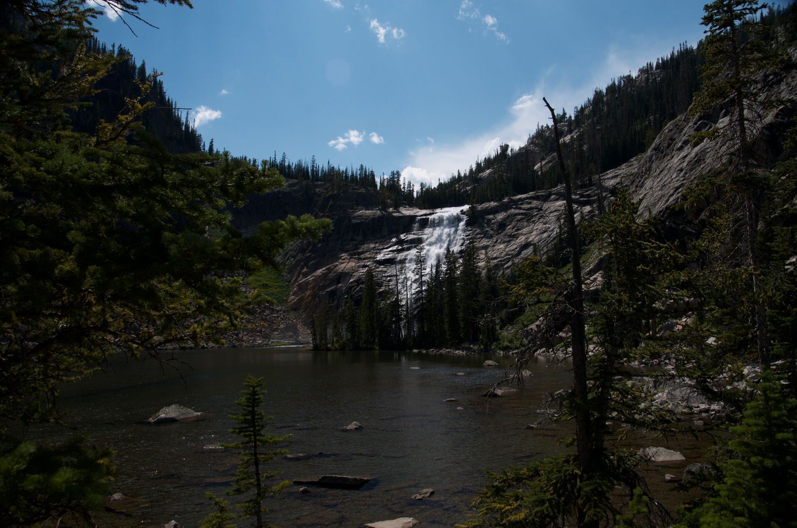 Dramatic waterfall cascading into alpine lake surrounded by granite slopes