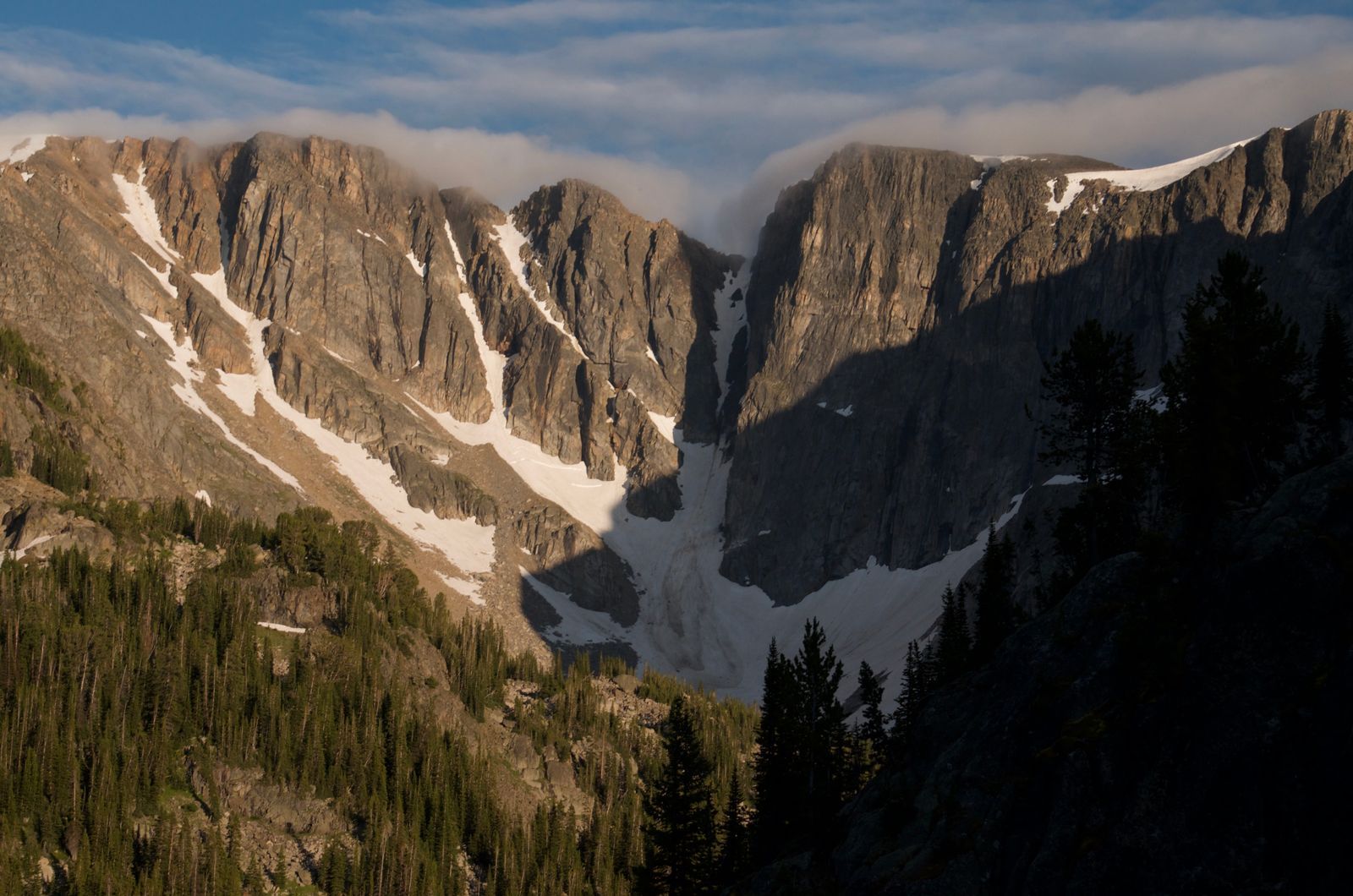 Massive Beartooth granite cliffs with snow couloirs and wisps of clouds