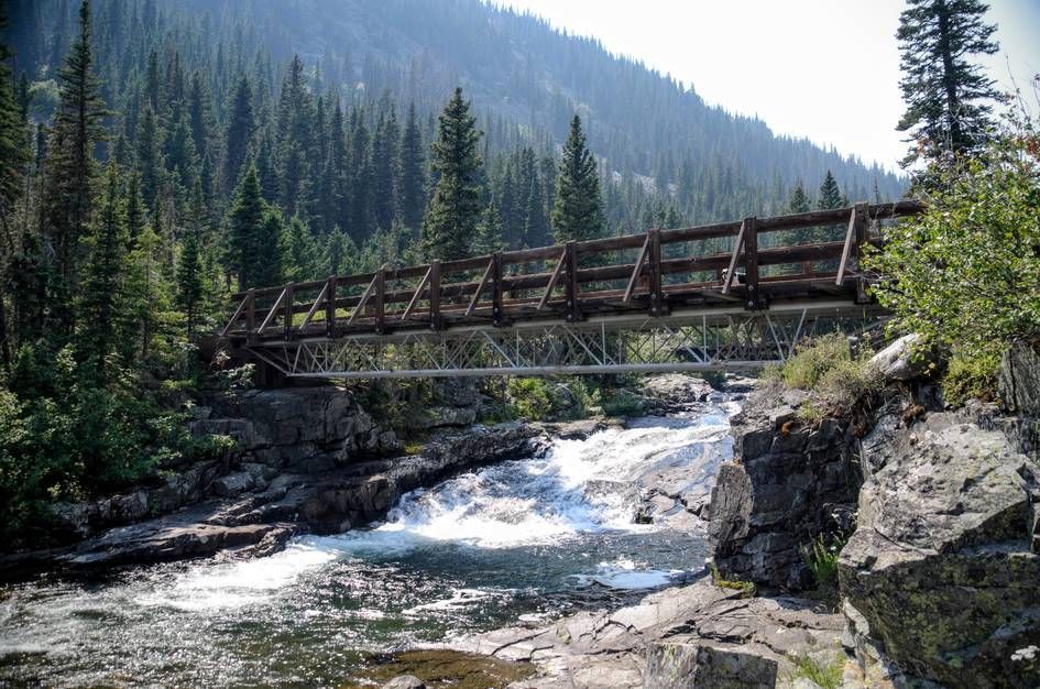 Metal footbridge over rushing Big Timber Creek with forested mountainside