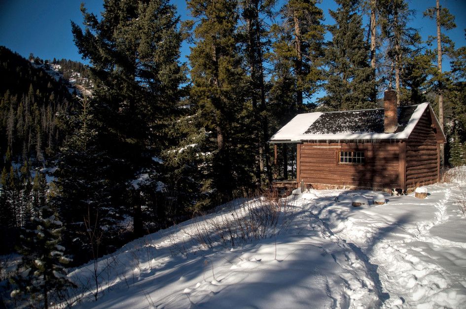 Mystic Lake Cabin in winter with snow, pine trees, and lake glimpses