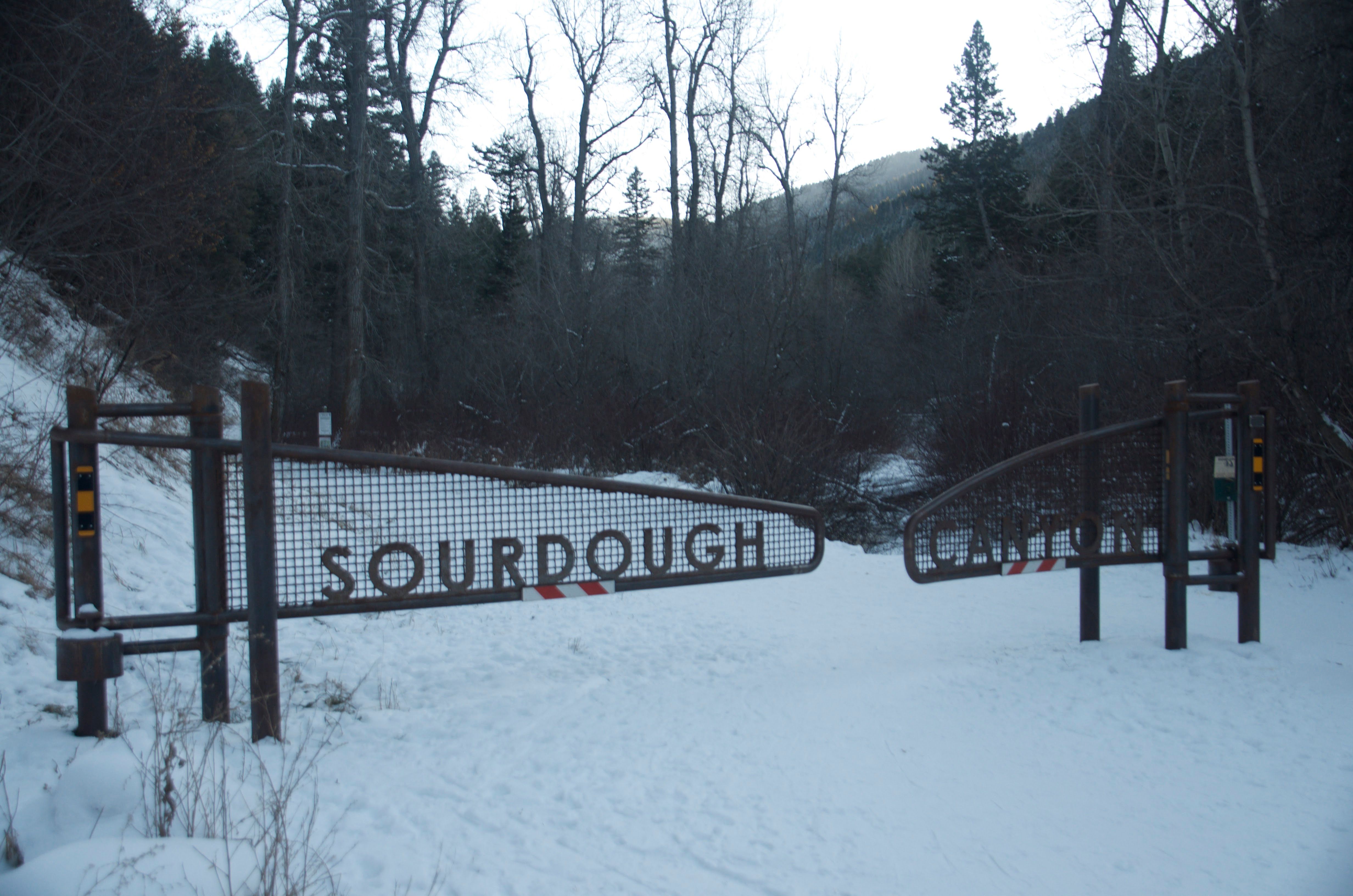 Sourdough trailhead gate with metal letters in winter snow