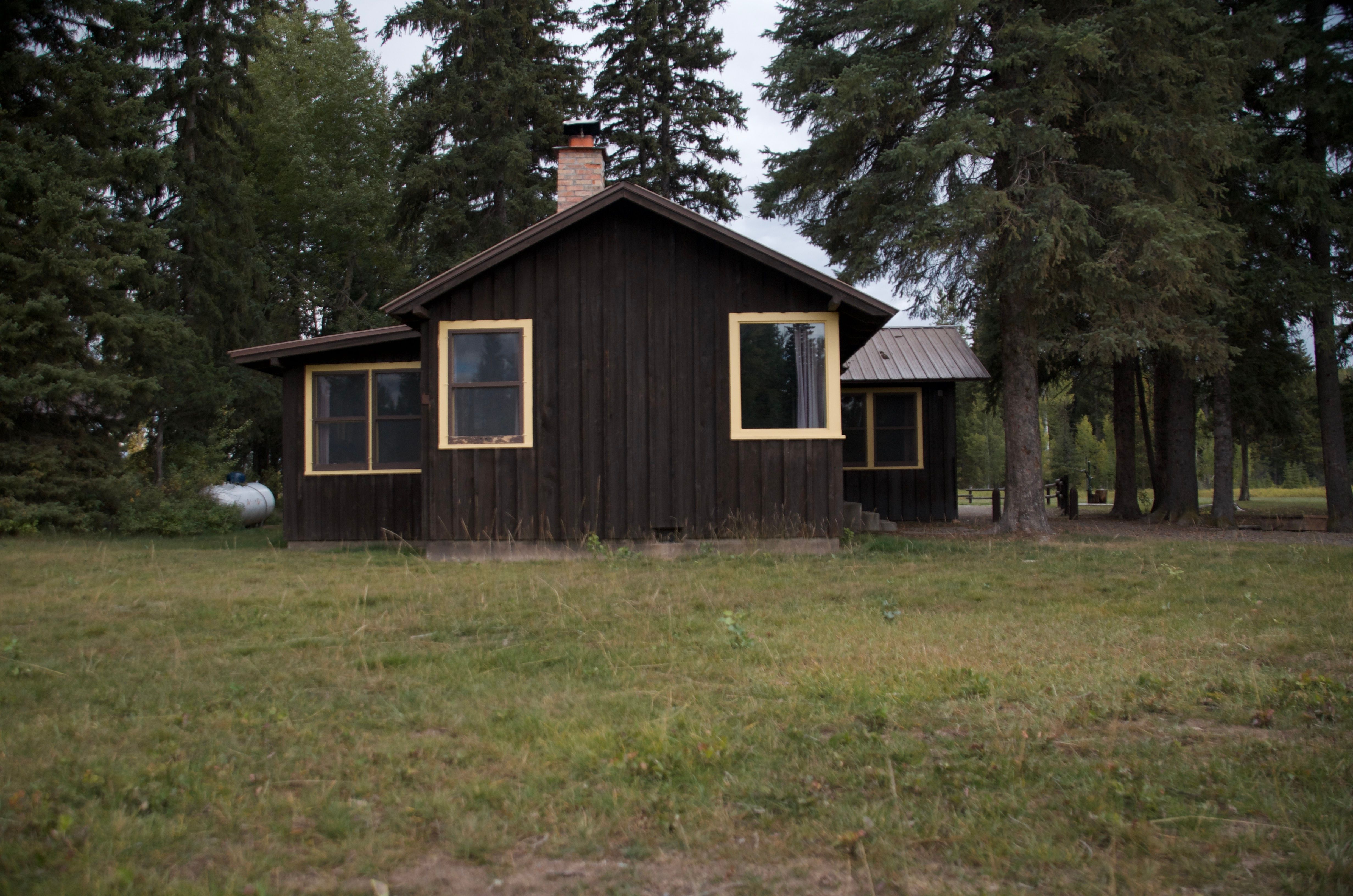 Ben Rover Cabin exterior, a dark wood Forest Service cabin in the trees near Polebridge