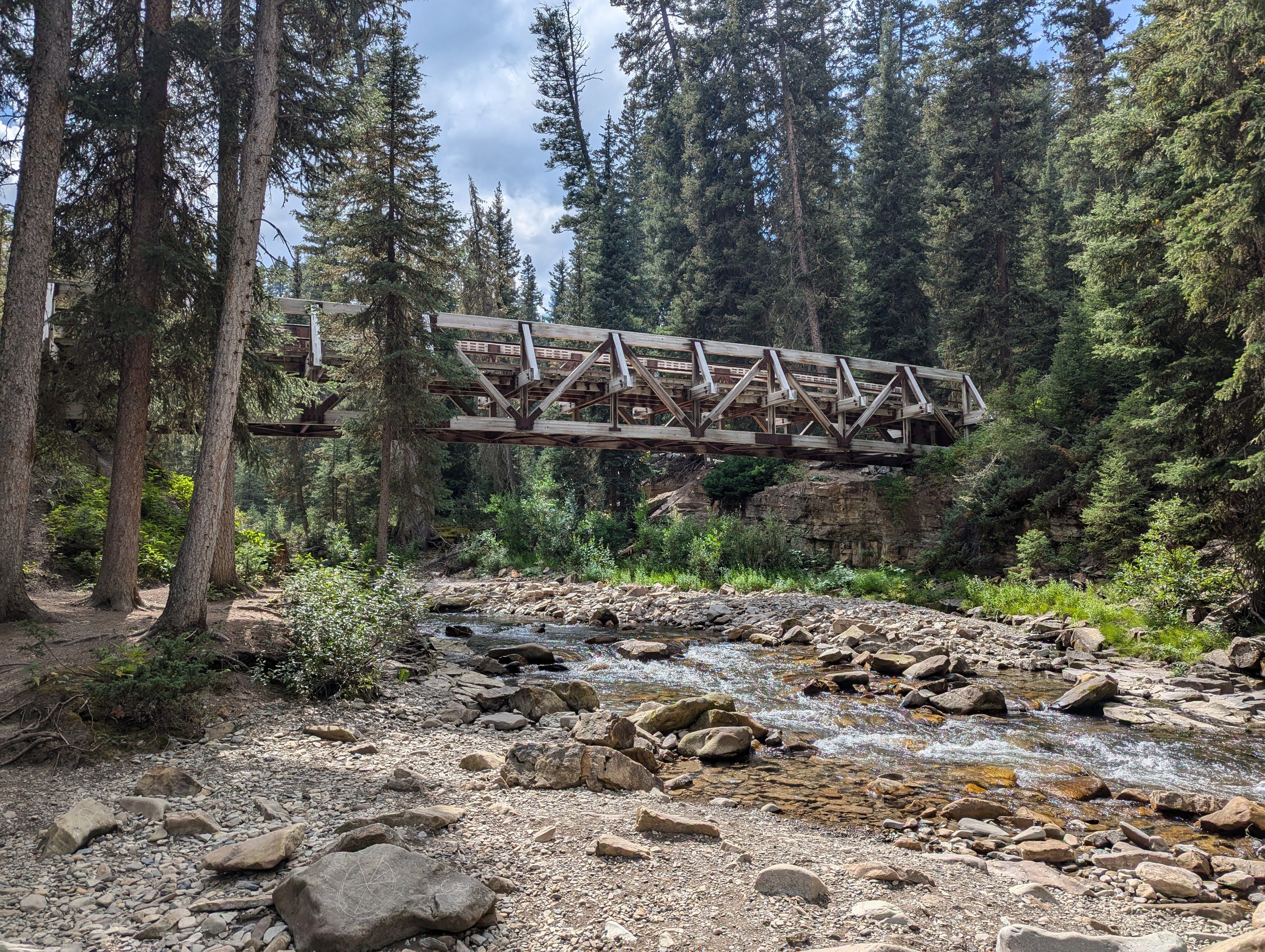 Wooden footbridge spanning the creek viewed from below with rocky streambed