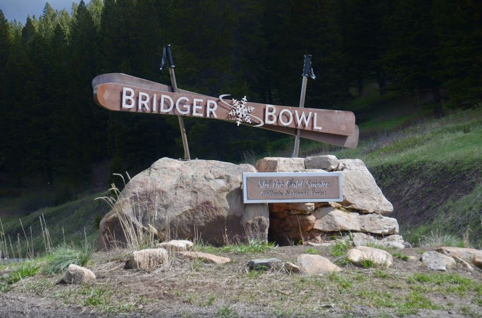Bridger Bowl ski area entrance sign with ski-shaped logo on stone base