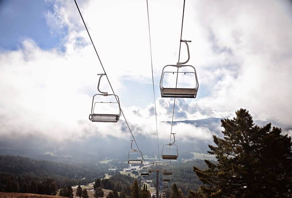 Empty ski chairlift ascending through dramatic clouds at Bridger Bowl