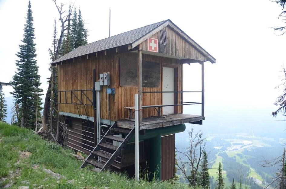 Wooden ski patrol hut with red cross symbol perched on mountainside