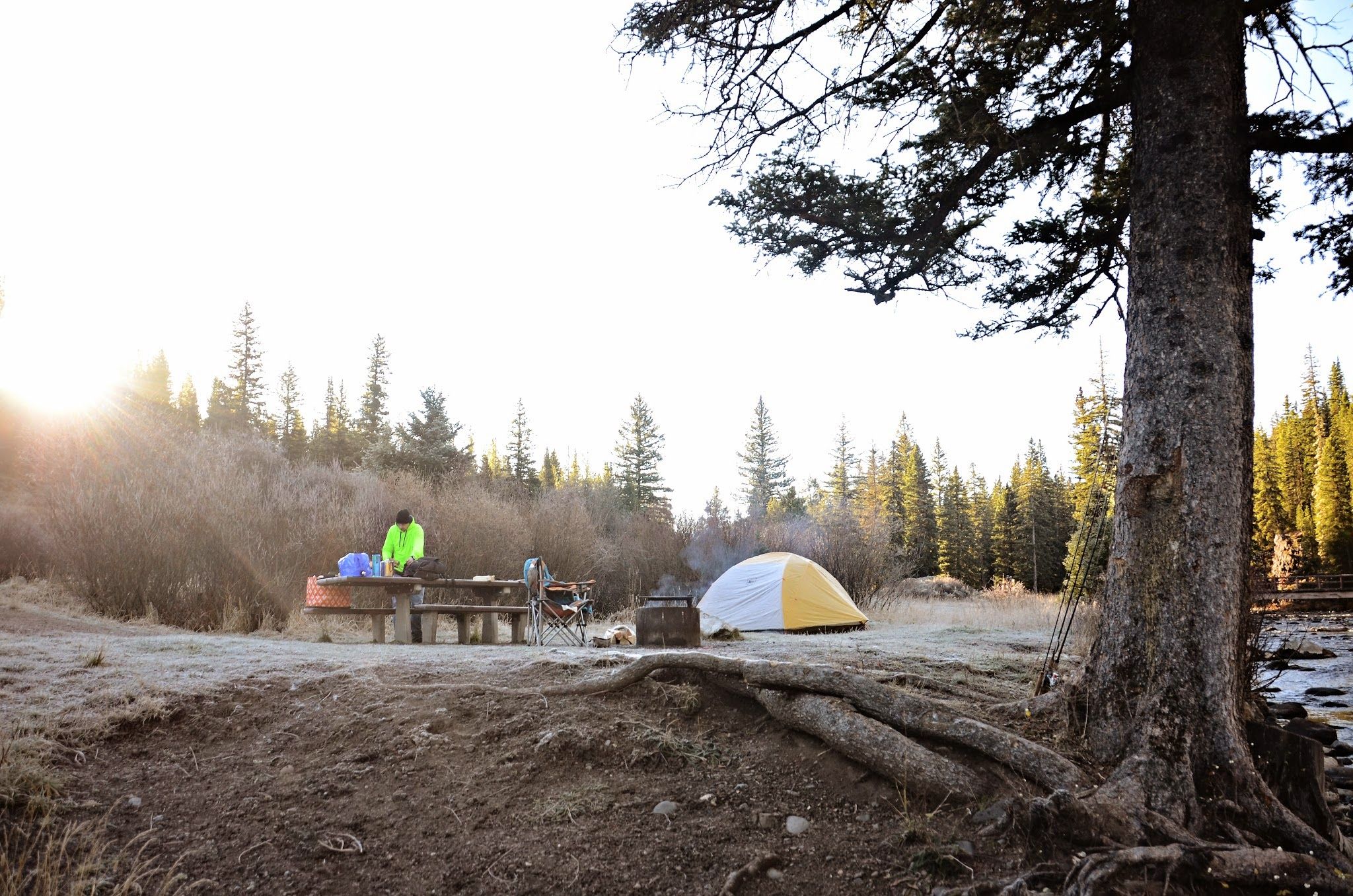 Early morning frost at a riverside campsite with tent and pine trees
