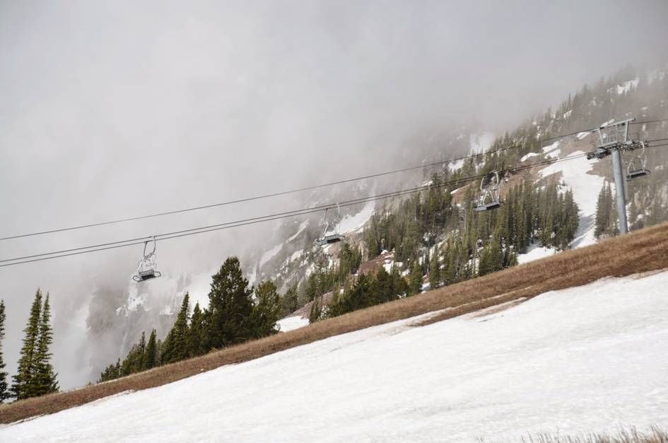 Ski chairlift with lingering spring snow patches and foggy mountains