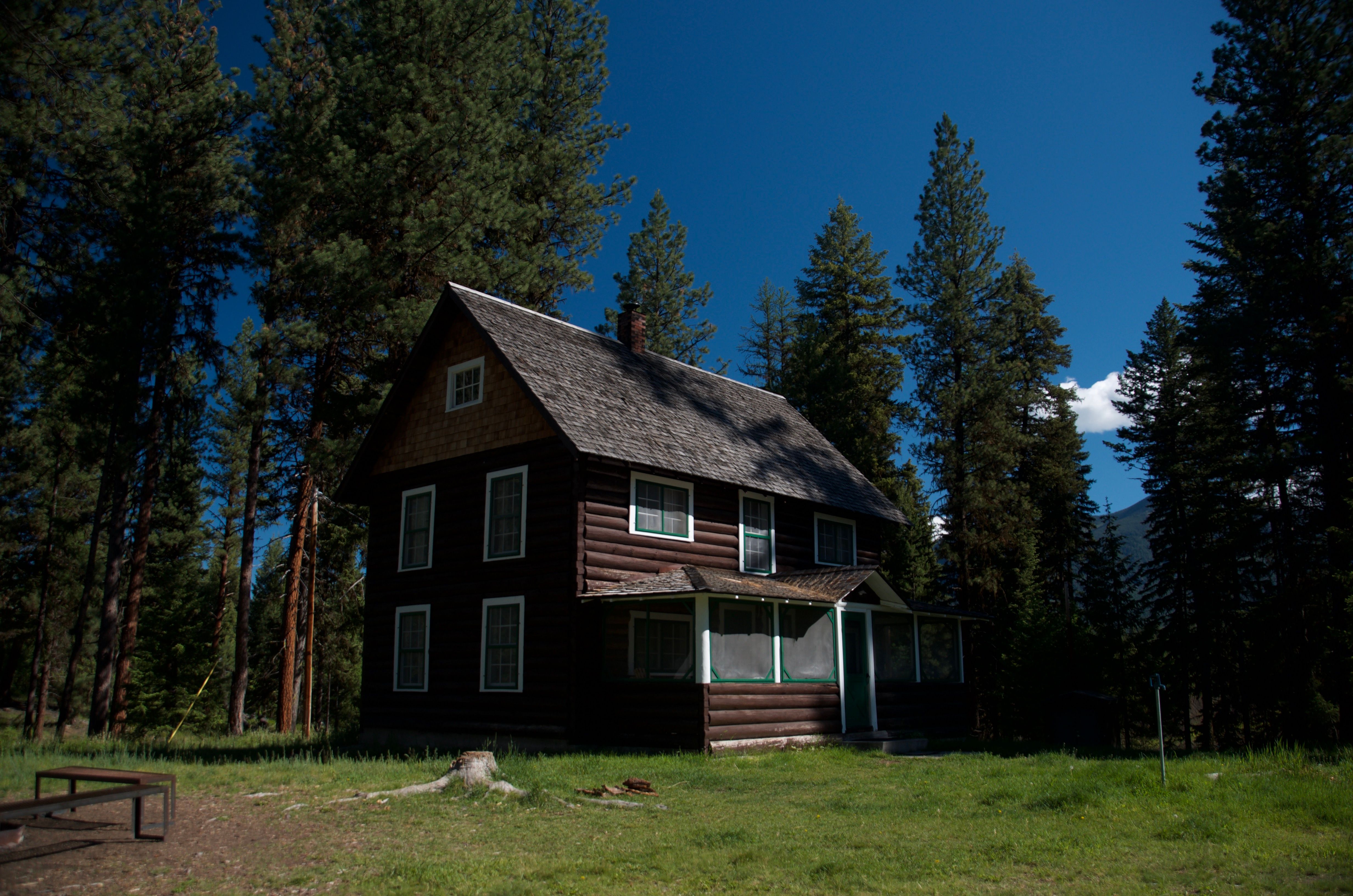 Old Condon Ranger Station exterior on a clear blue sky day with large pine trees framing the two-story cabin