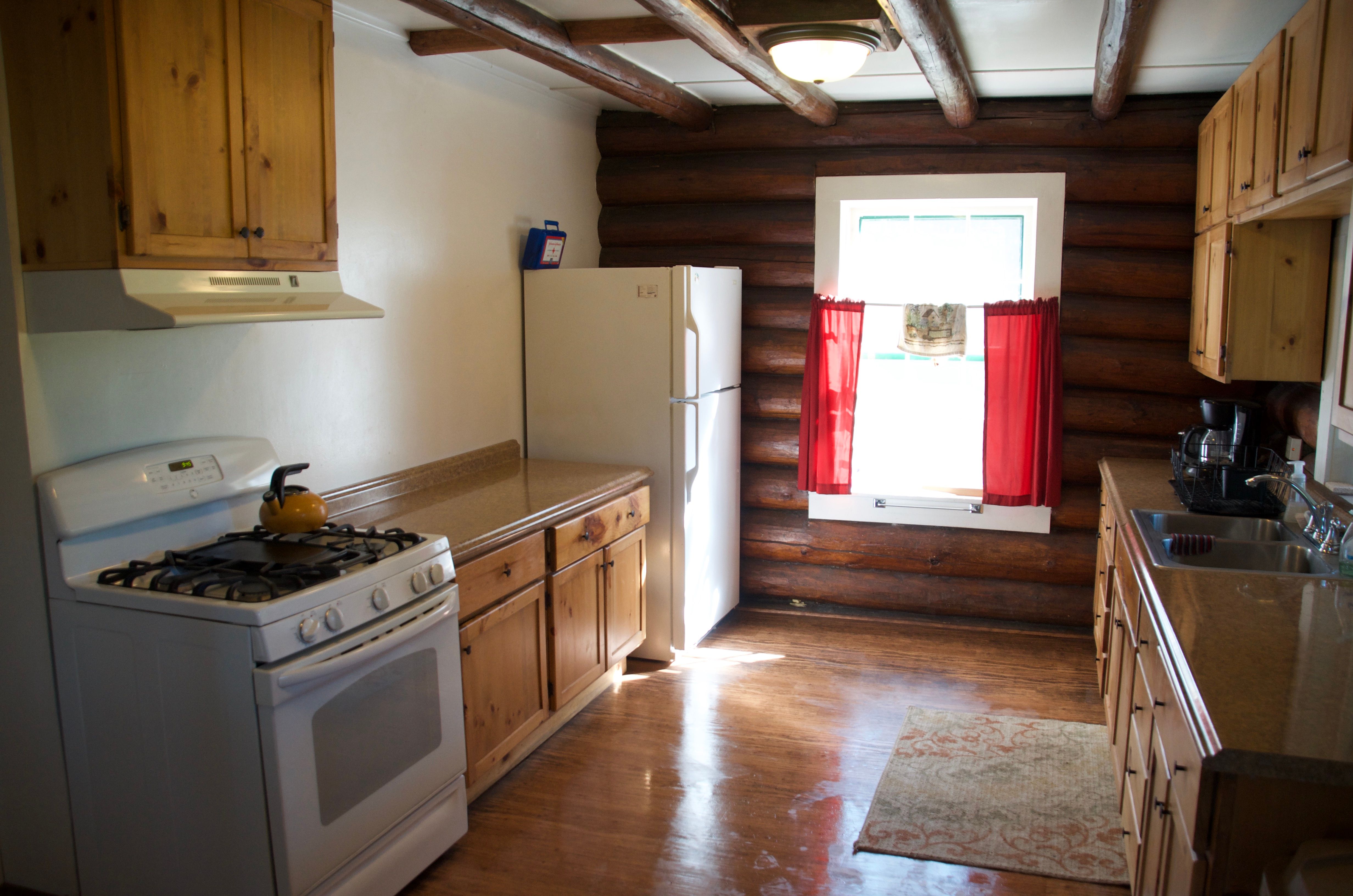 The Condon Ranger Station kitchen with gas range, full-size refrigerator, and original log walls