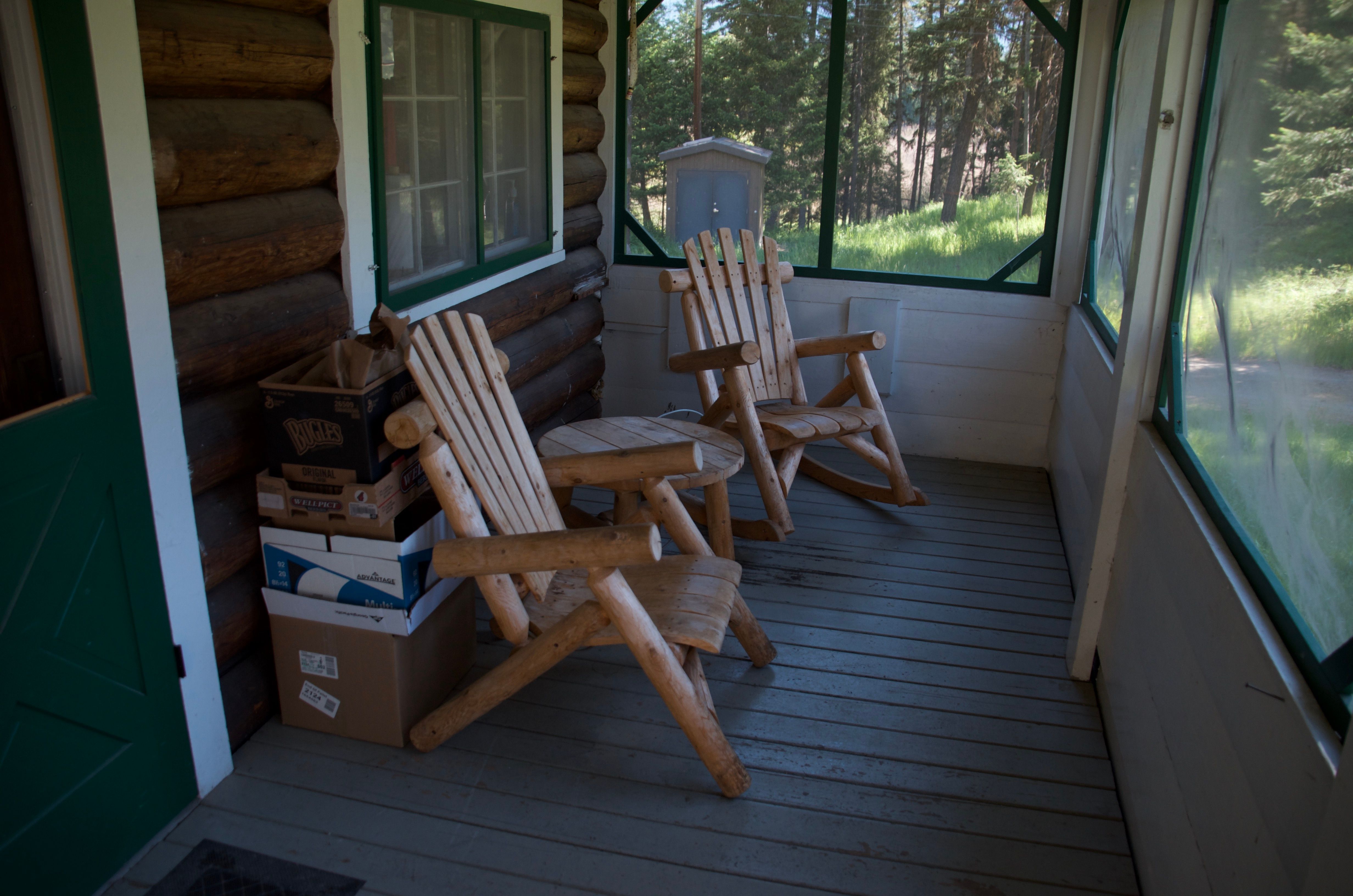 Screened front porch with two log rocking chairs looking out toward the trees