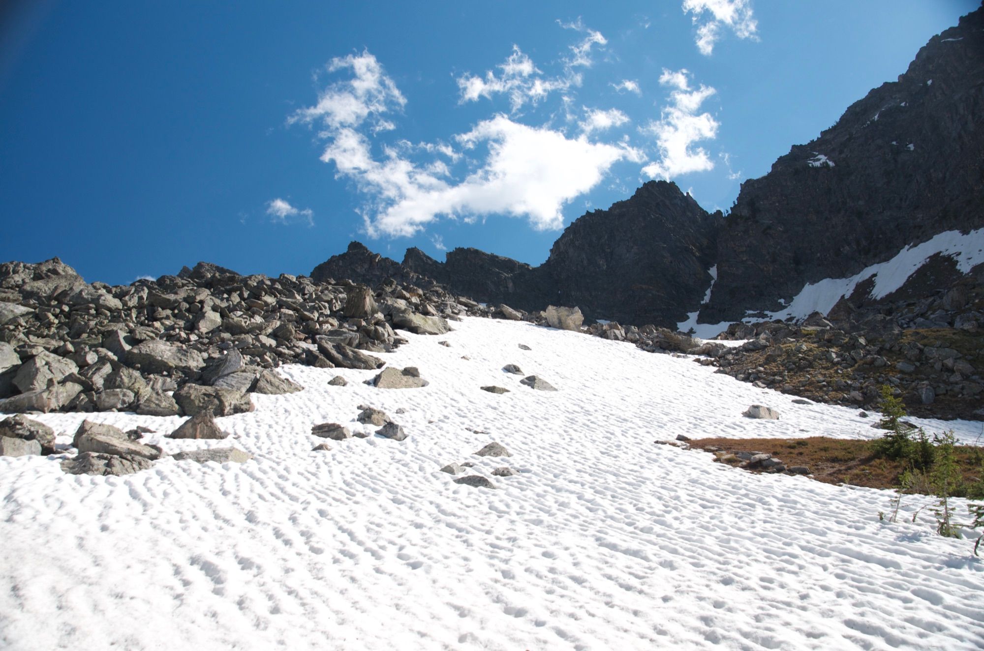 Snow field leading up to rocky talus and rugged peaks
