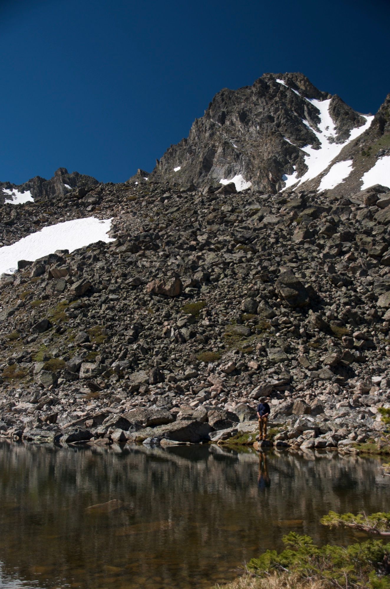 Rocky cliffs and snowfields reflected in Spanish Lakes
