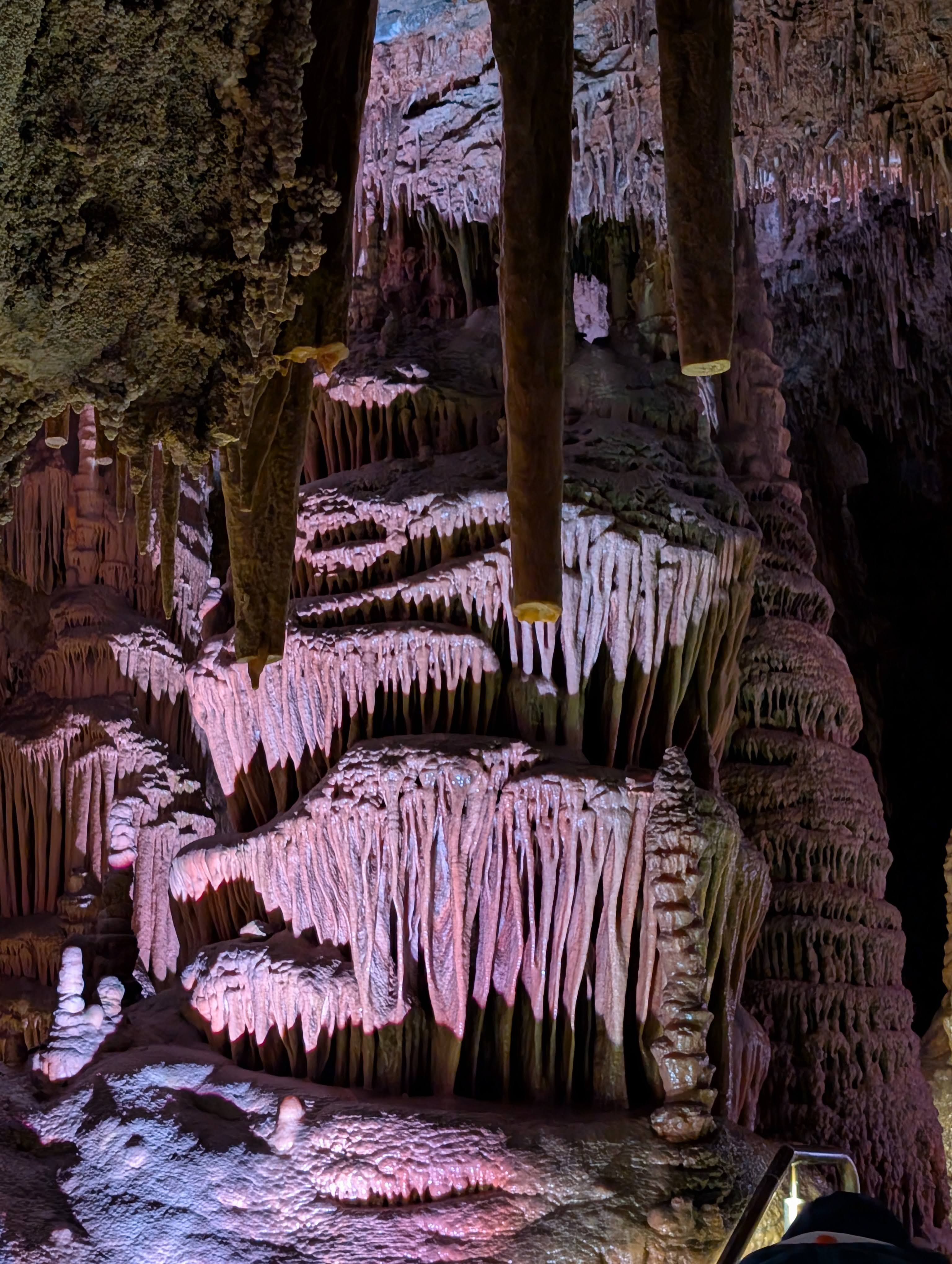 Dramatic stalactites and stalagmites with pink and purple lighting