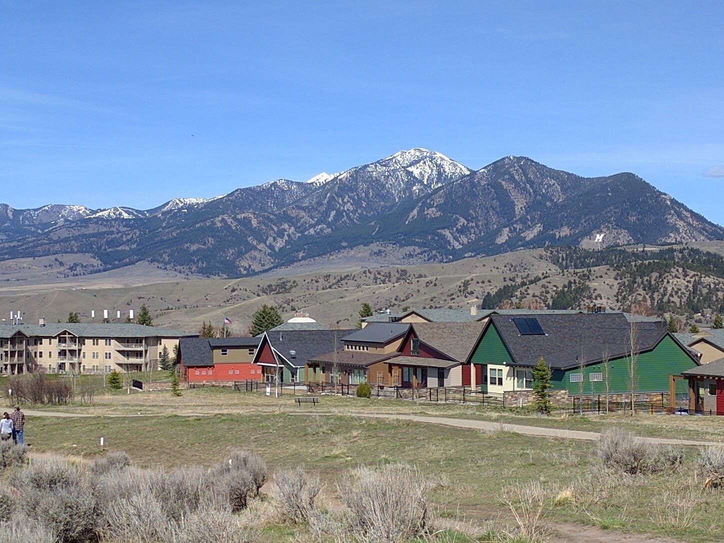 Spring view from Peets Hill looking toward snow-capped Gallatin Range peaks with colorful Bozeman neighborhood buildings in the foreground