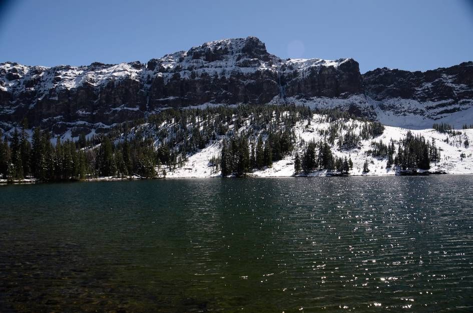 Heather Lake with dramatic rocky cliffs and snow-dusted evergreen shoreline