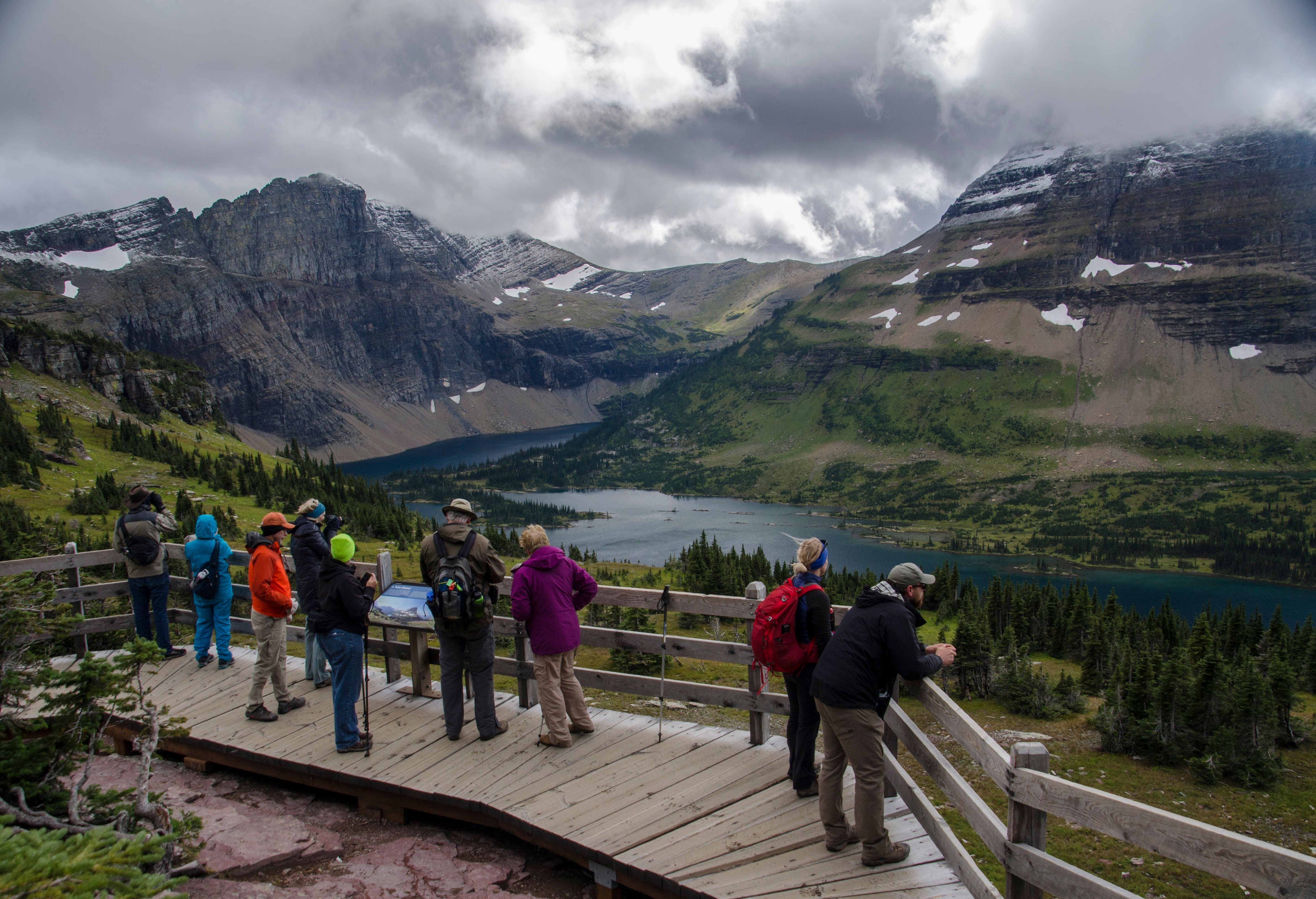 Crowded overlook deck packed with hikers viewing Hidden Lake and Bearhat Mountain