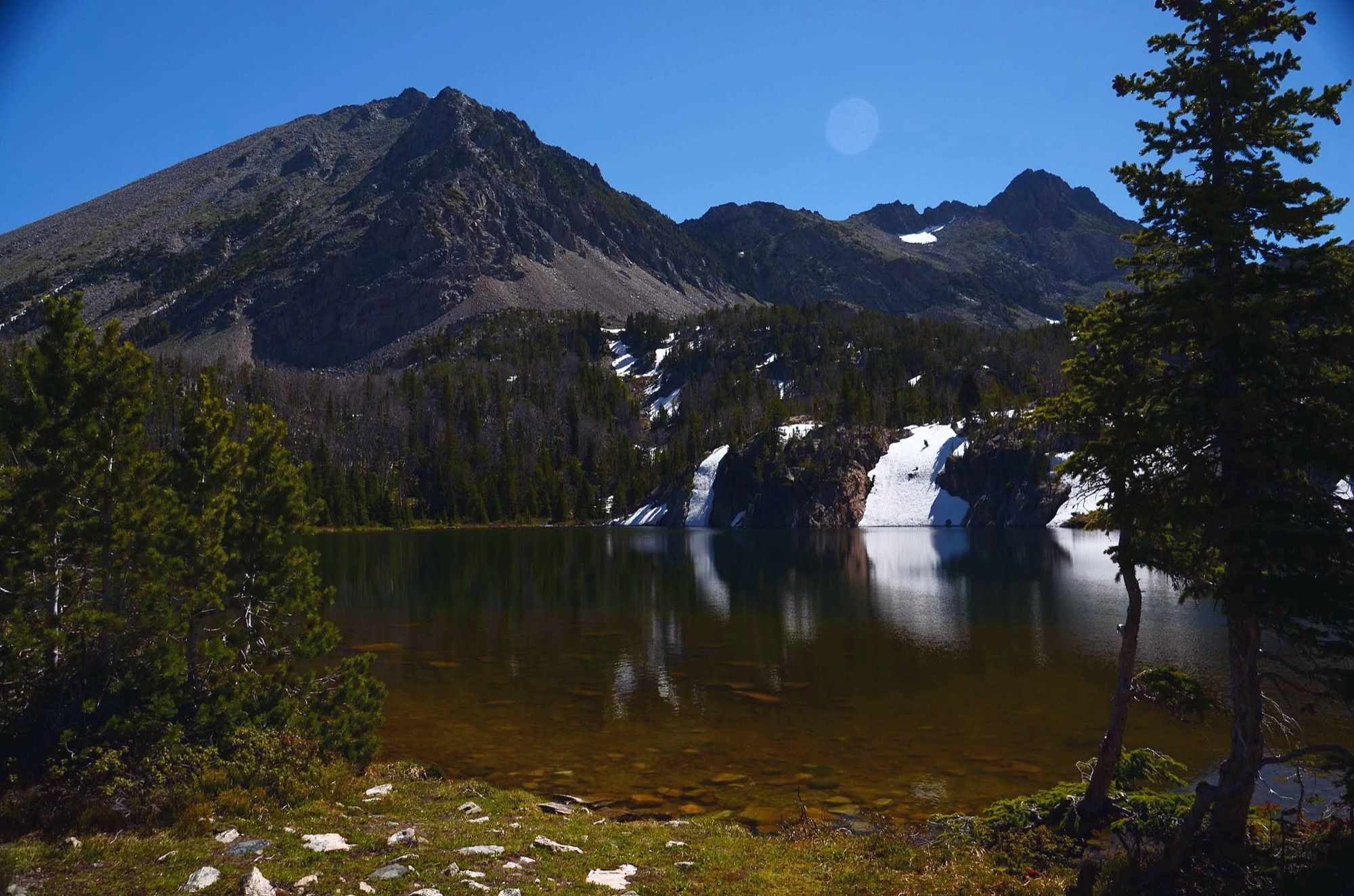 Spanish Lakes framed by evergreen trees with peaks and moon above