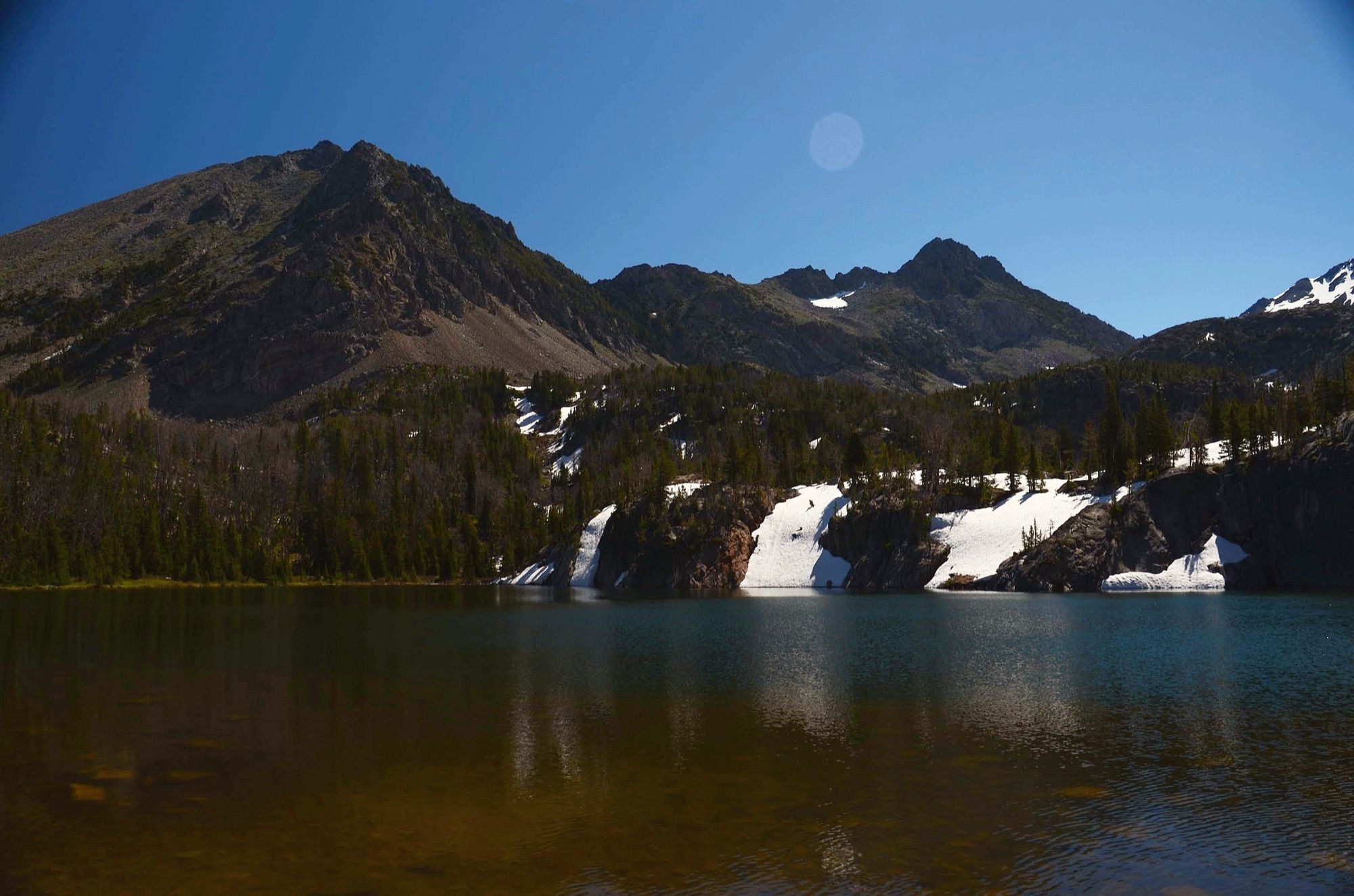 Spanish Lakes with peaks, snowfields and reflections under blue sky