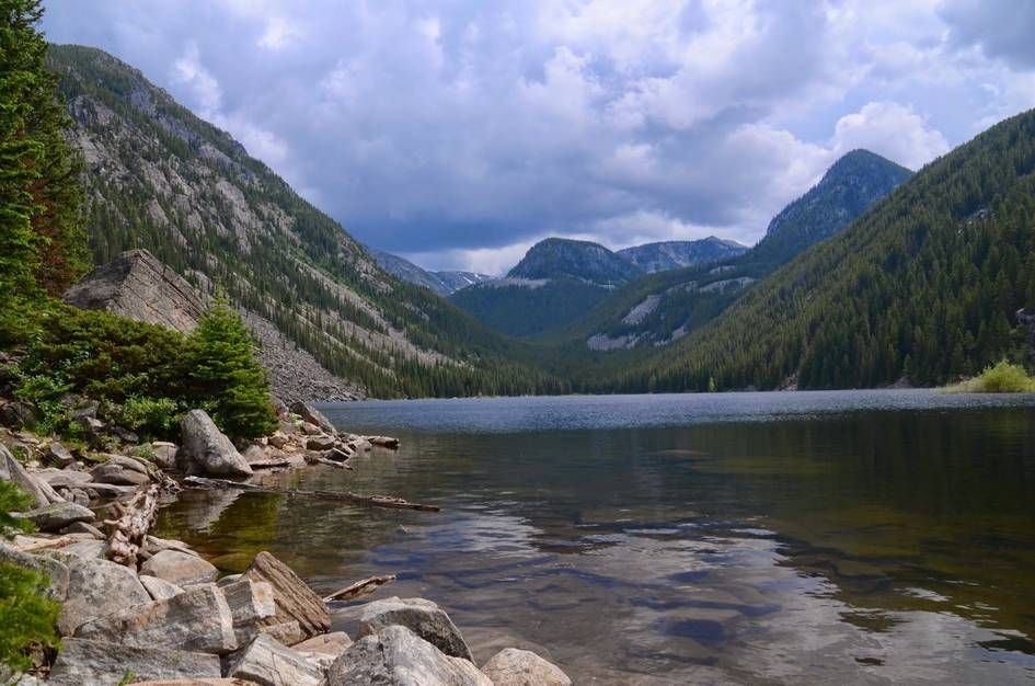 Lava Lake reflecting forested mountain slopes under cloudy sky