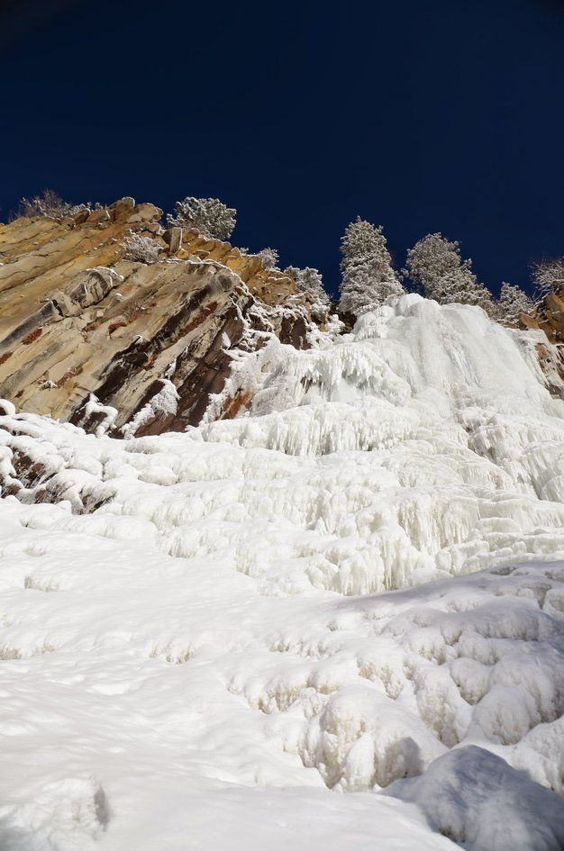 Frozen waterfall and columnar basalt cliff against deep blue sky