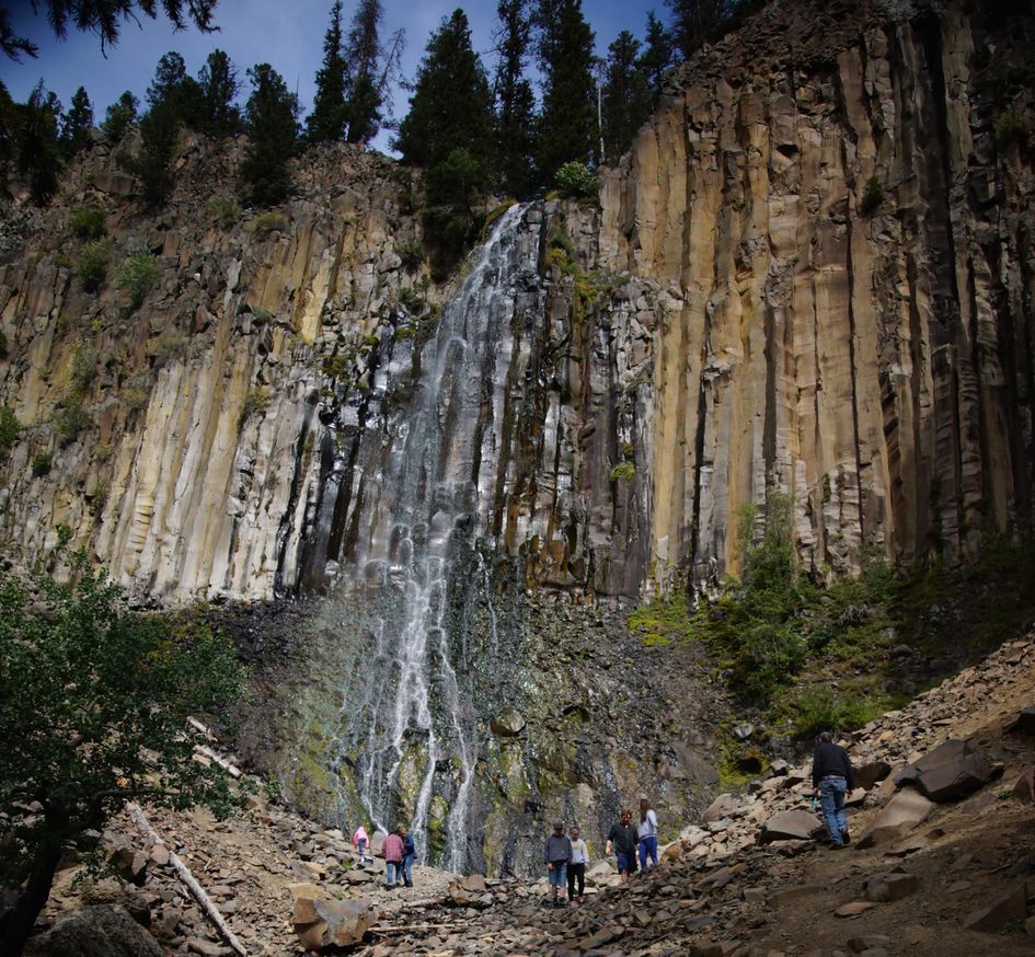 Visitors viewing Palisade Falls in summer from the rocky viewpoint