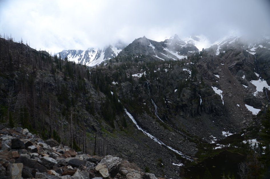 Rugged Absaroka peaks with waterfalls and snow fields beneath stormy clouds