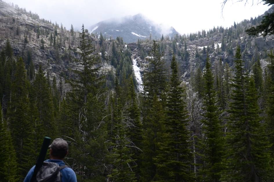 Distant waterfall cascading down granite cliffs with cloud-shrouded peak behind