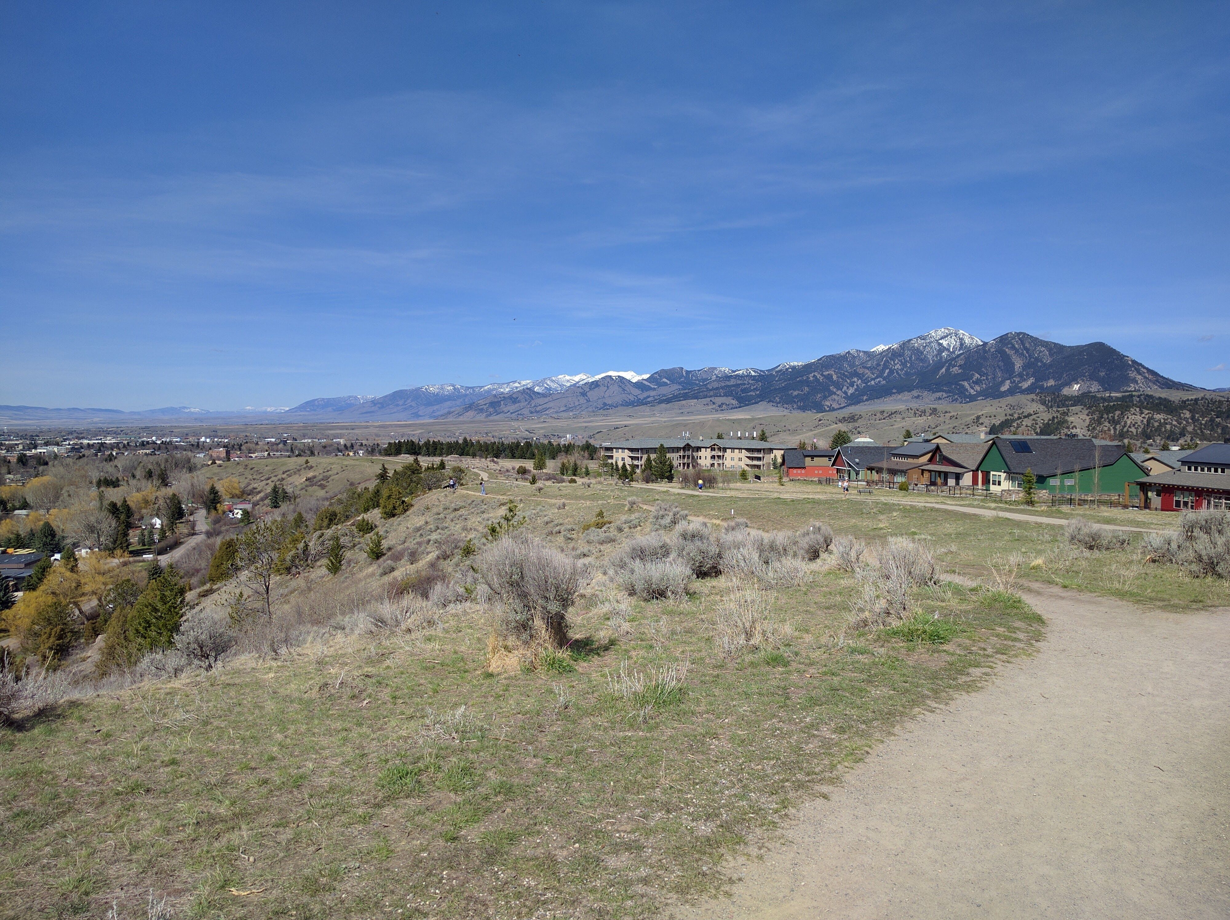 Gravel trail along the Peets Hill ridgeline with sagebrush hillside and snow-capped Gallatin Range in the distance