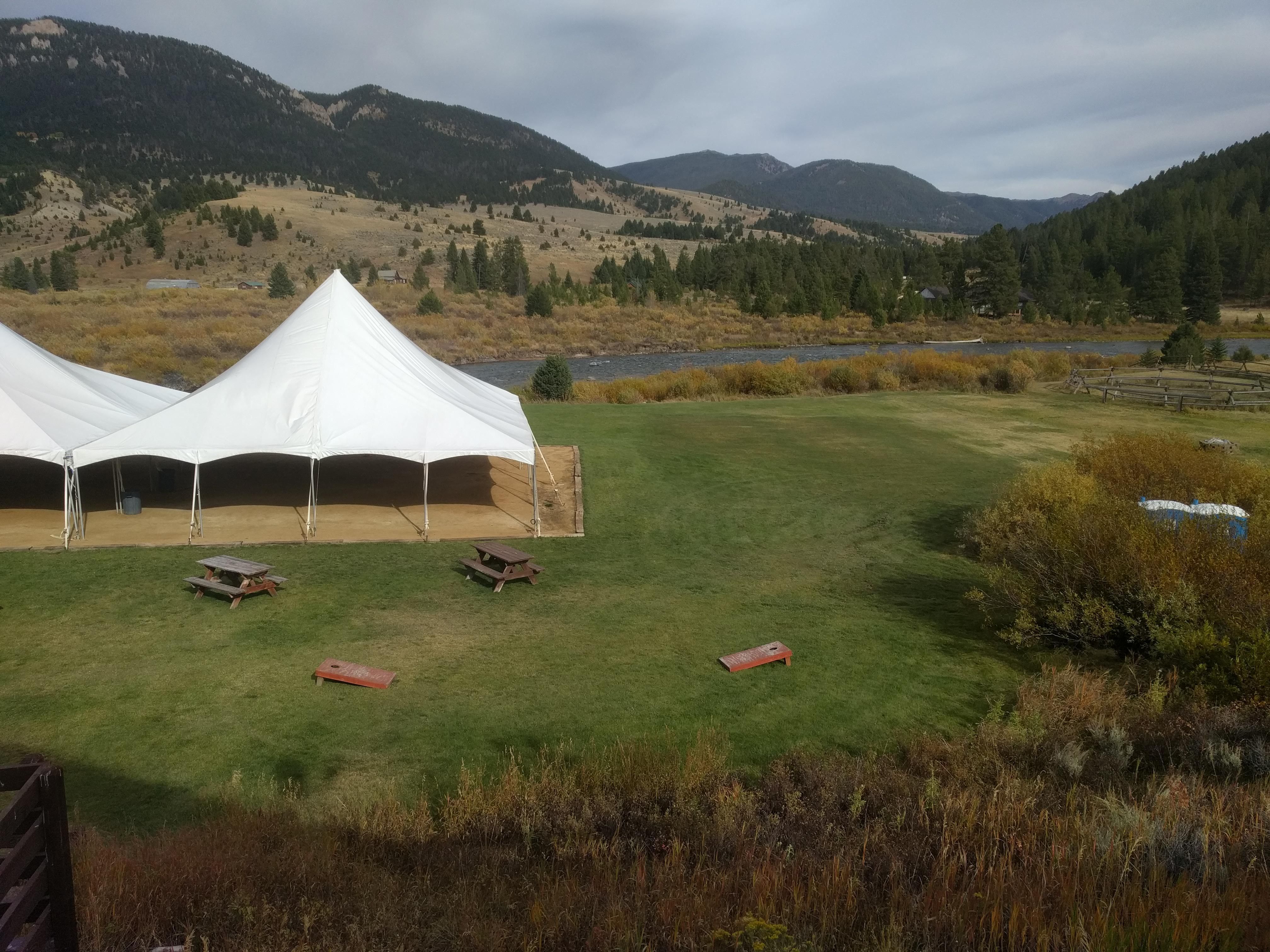 Riverhouse BBQ lawn area with event tent, cornhole boards, and Gallatin River views