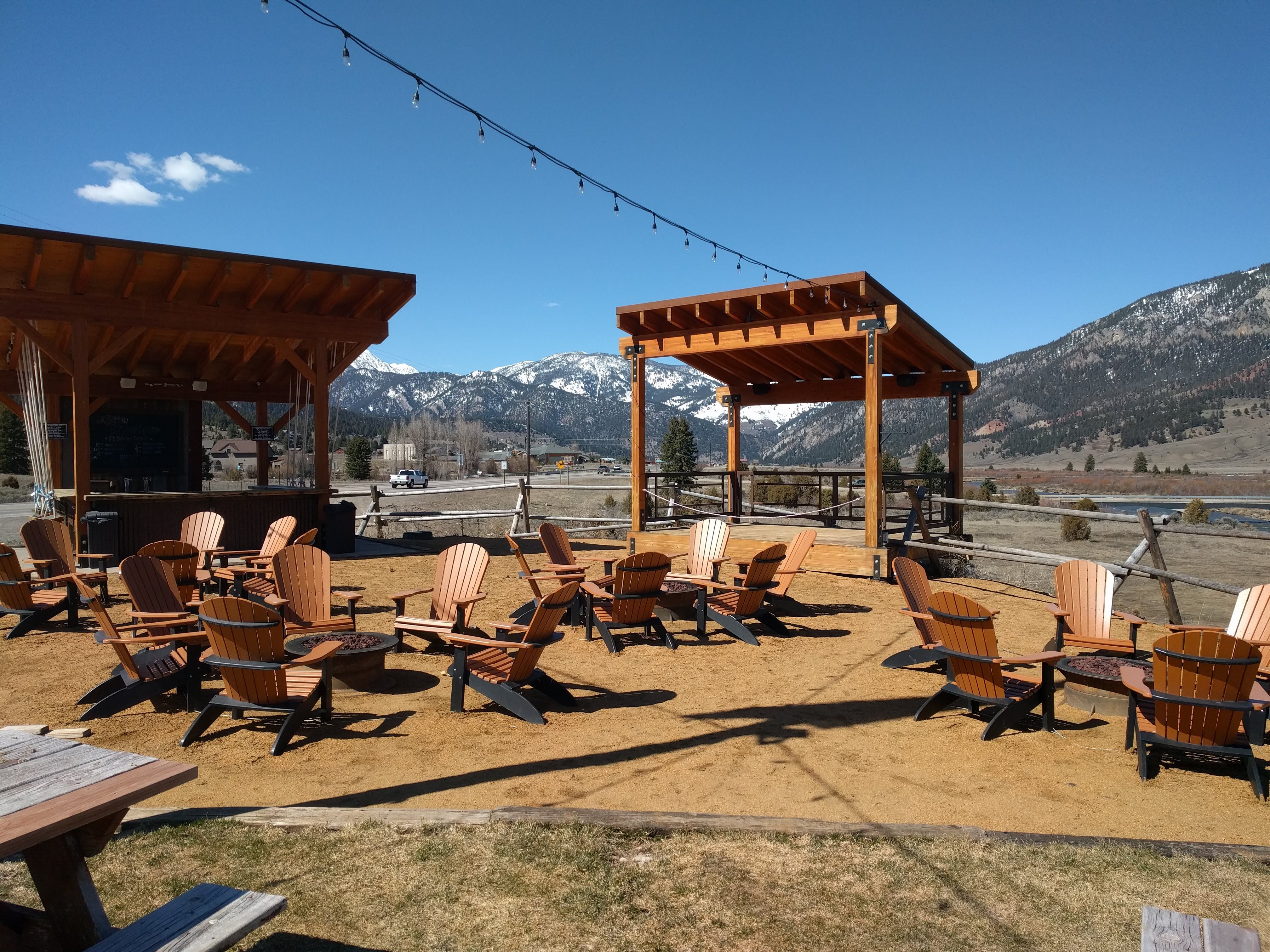 Riverhouse BBQ fire pit area with wooden chairs and string lights