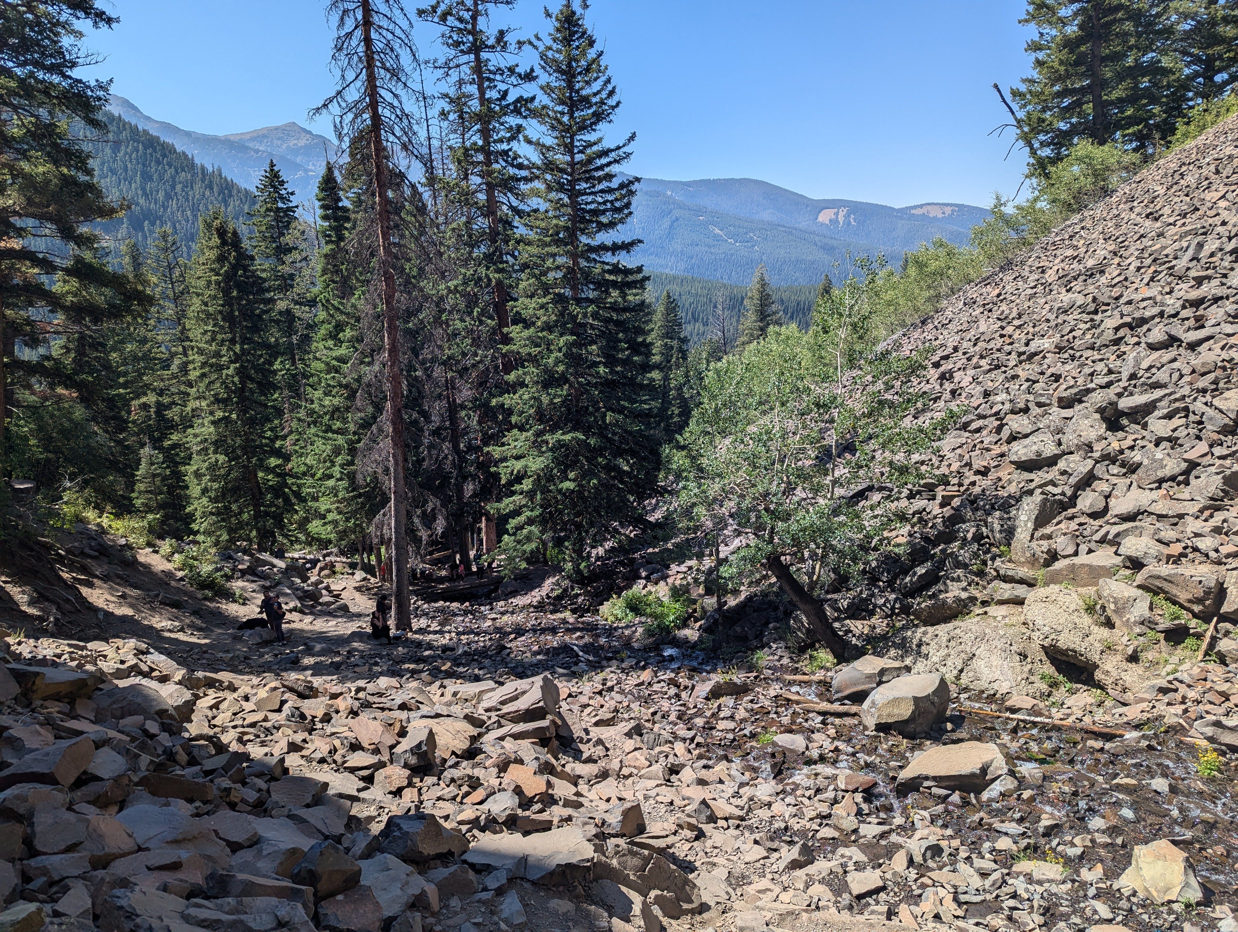 Rocky trail through talus field with mountain views in the distance