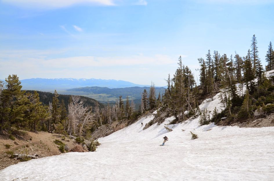 Backcountry skiers descending spring snow with valley and distant mountains