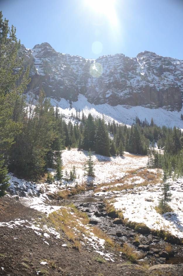 Hyalite Creek flowing through snowy alpine basin with rocky peaks above