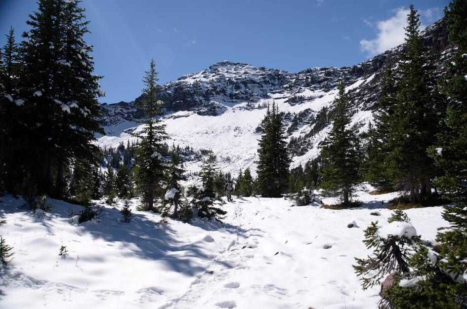 Snow-covered trail through alpine terrain with rocky peak ahead