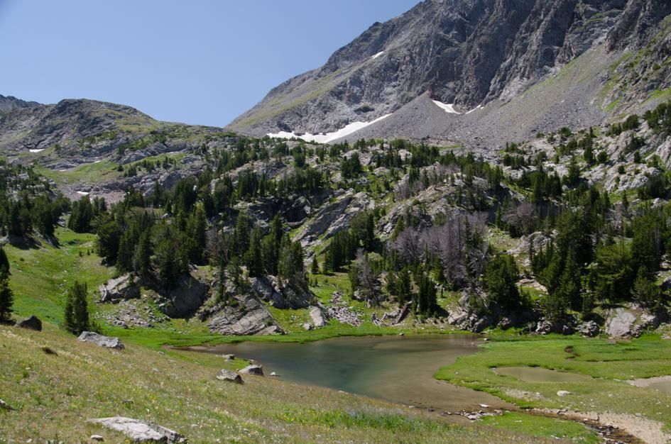 Tumbledown Lake in alpine cirque with snow patches and rocky cliffs above